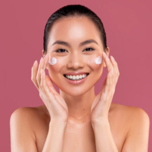 Young asian woman applying moisturizer cream on he g2n9b3y